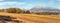 Mount Krivan peak Slovak symbol with blurred autumn coloured trees and dry field in foreground wide panorama, Typical