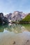Mount Seekofel and wooden boats mirroring in the clear calm water of iconic Pragser Wildsee Lago di Braies in Dolomites, Unesco