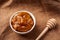 Mountain Altai honey in a white bowl next to a wooden ribbed honey stick