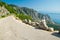 Mountain asphalt road on the top of peak Sveti Jure in front of hills and rocks of Biokovo mountain range and Makarska riviera