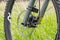 Mountain bike front wheel with large hydraulic brake rotor. Against a background of blurred green grass