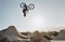 Mountain bike jump training man on rocks hill cycling in air, blue sky mockup for professional performance, training or