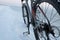 Mountain bike stay in snow near frozen sea or lake. Rear wheel shifter and disk breaks detail. Winter bicycle