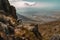 mountain biker scaling steep and rocky terrain, with view of sprawling landscape in the background