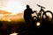 Mountain biker standing on top of a mountain with a bicycle, a beautiful sunset. Silhouette of a cyclist