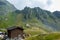 Mountain chalet in the foreground with mountain and sheep eating grass near mountain rescue house in the background