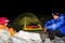 Mountain climber couple sit outside a tent in the dark and drink tea high up in the Cordillera Blanca in the Andes of Peru