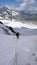 Mountain climber exiting a steep north face in the Swiss Alps and hiking up a glacier to the summit