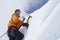 Mountain Climber Going Up Snowy Slope With Axes