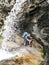 Mountain climber hiking under a waterfall on a rocky hiking trail