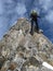 Mountain climber rappelling off a steep and narrow rock ridge leading down from a high peak in the Swiss Alps