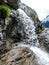 Mountain climbers hiking under a waterfall on a rocky hiking trail
