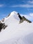 Mountain climbers on a steep and narrow snow ridge leading to a high peak in the Swiss Alps