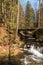 Mountain creek with small water cascades, bridge above, trees around and clear sky in Moravskoslezske Beskydy mountains in Czech