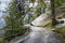 Mountain curve road covered with frosted snow and green meadows