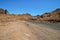 Mountain desert landscape, mountains of red sandstone, a plain covered with rare desert vegetation, a stretch of road