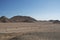 Mountain desert landscape, sandstone mountains, plain covered with rare desert vegetation, against a cloudless blue sky