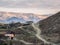 Mountain dirt winding road with rural houses on the hillside. Morning view of a mountain valley with a serpentine road. Matlas