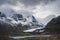 Mountain glacier with lake in gloomy cloud