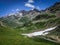 Mountain grassy ranges with rocky hills and snow. Trekking in summer