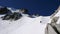 Mountain guide and client climbing a steep snow ridge on a north face in the Alps above Chamonix