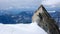 Mountain guide and client walk along a narrow snow ridge with a giant rock needle and a fantastic view behind t