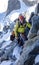 Mountain guide leading male client to the summit of a high alpine peak on a beautiful summer day