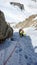 Mountain guide leading male client to the summit of a high alpine peak on a beautiful summer day