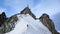 Mountain guide and a male client on a snow ridge heading down from a high summit in the French Alps near Chamonix