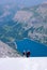 Mountain guide with two clients descending a steep white glacier with a fantastic blue mountain lake far below