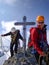 Mountain guide and woman client arrive at the summit cross of a high alpine peak in the Swiss Alps
