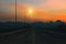 Mountain highway. Amazing landscape with rocks, sunset sky and asphalt road going to horizon at the evening. Summer adventure.