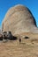 Mountain hiker with backpack approaches giant stone rock