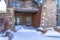 Mountain home facade with balcony over double glass doors and snowy entrance