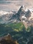 A mountain hut at the edge of a cliff with a green valley below and snow-covered mountains Swiss Alps in the background with