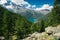 Mountain lake landscape with conifer of fir and larch, mountain range in background. View to Ceresole Reale. Italian Alps