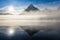 Mountain lake with reflection and fog at sunrise in Jasper National Park, Alberta, Canada The clouds and sun reflect