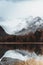 Mountain lake with reflection in the mirrored surface of the rocks in cloudy rainy weather.