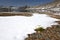 Mountain lake, snow, stones and yellow flowers