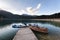 Mountain lake sunrise landscape.Old wooden boat and blue kayaks at the plank