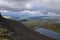 Mountain lake in valley with mosses and rocks covered with lichens. Cloudy sky before storm.  Khibiny mountains above the Arctic