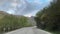 mountain landscape with blue sky, hilltops and natural green forests, road trip