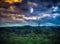 Mountain landscape covered with green tree forest. Night sky with full moon behind partial cloudy