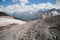 Mountain landscape dusty dirty volcanic slope with a cracked melting glacier against the backdrop of the Caucasus