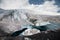 Mountain landscape dusty dirty volcanic slope with a cracked melting glacier against the backdrop of the Caucasus