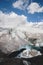 Mountain landscape dusty dirty volcanic slope with a cracked melting glacier against the backdrop of the Caucasus