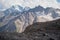 Mountain landscape dusty dirty volcanic slope with a cracked melting glacier against the backdrop of the Caucasus