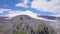 Mountain landscape with snowy peak and rocky foothills. Clip. Stunning view of snowy mountain in clouds on background of