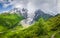 Mountain landscape on sunny summer day. Mount Tetnuldi and glacier Lardaad. Svaneti mountains and green hills