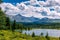 Mountain landscape, white clouds, lake and mountain range in the distance. Fantastic sunny day in mountains, large panorama.